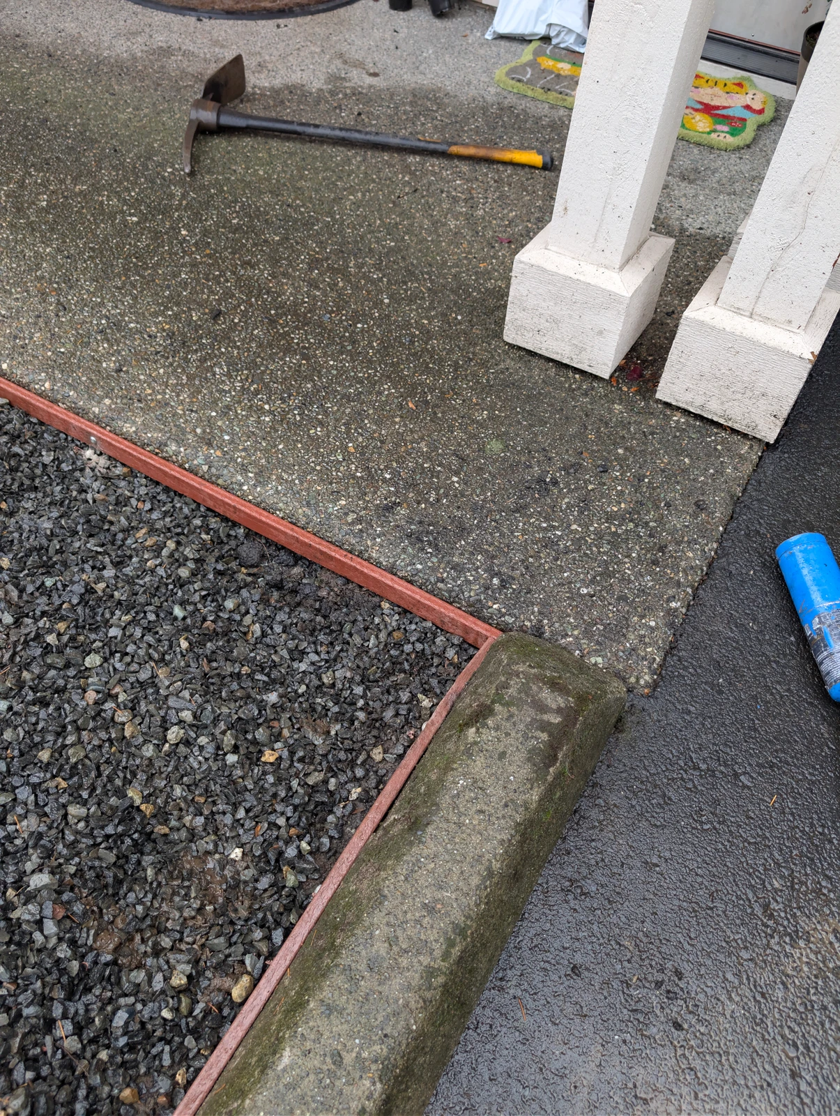 Concrete porch edged with red metal border separating gravel area, prep work for K9Grass Elite pet turf installation, Marysville WA