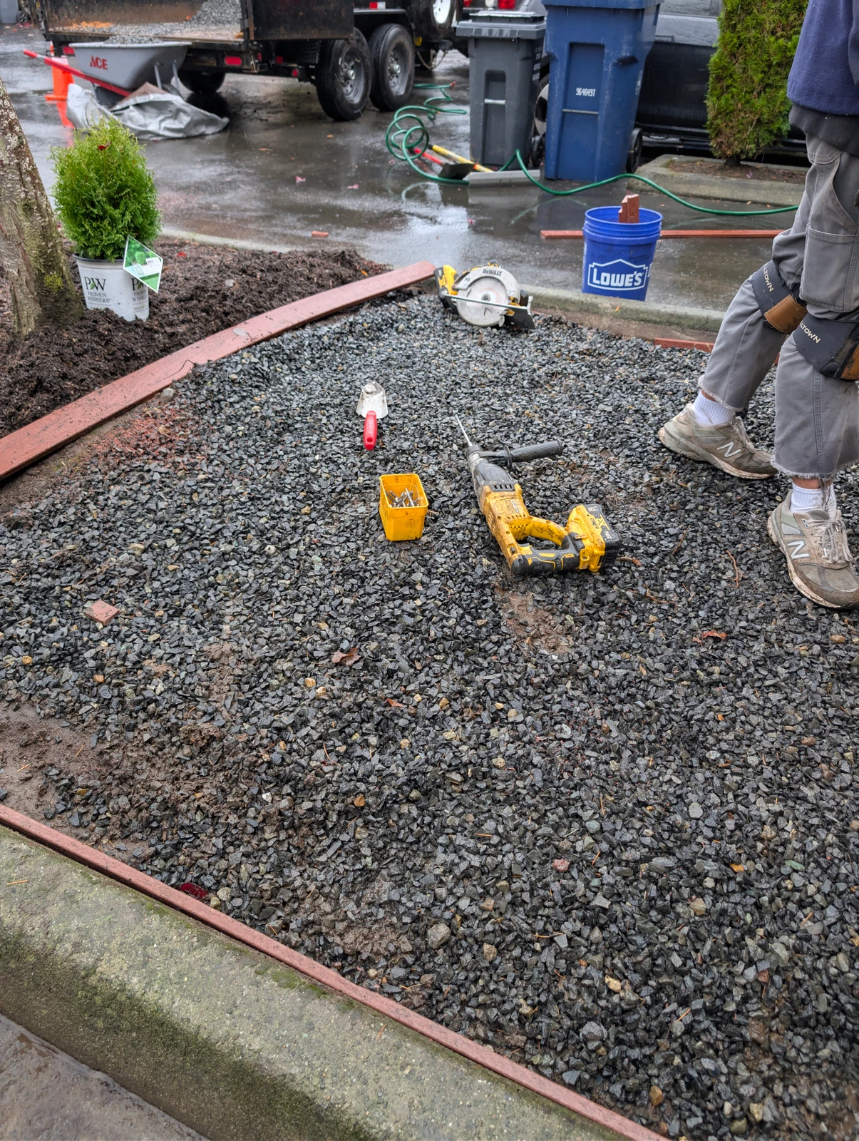 Crushed gravel base layer with red metal edging installed in residential yard, DeWalt tools on site, Marysville WA pet turf prep