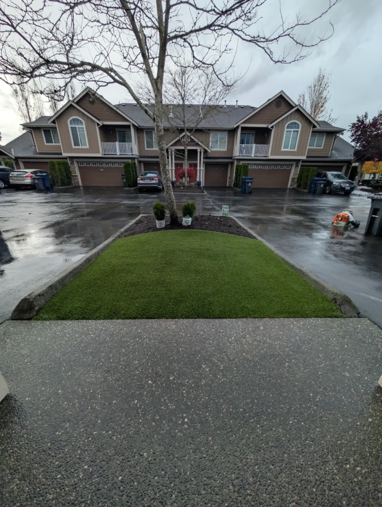 Freshly installed K9Grass Elite artificial pet turf patch in parking island with tree and shrubs, Marysville WA townhomes.