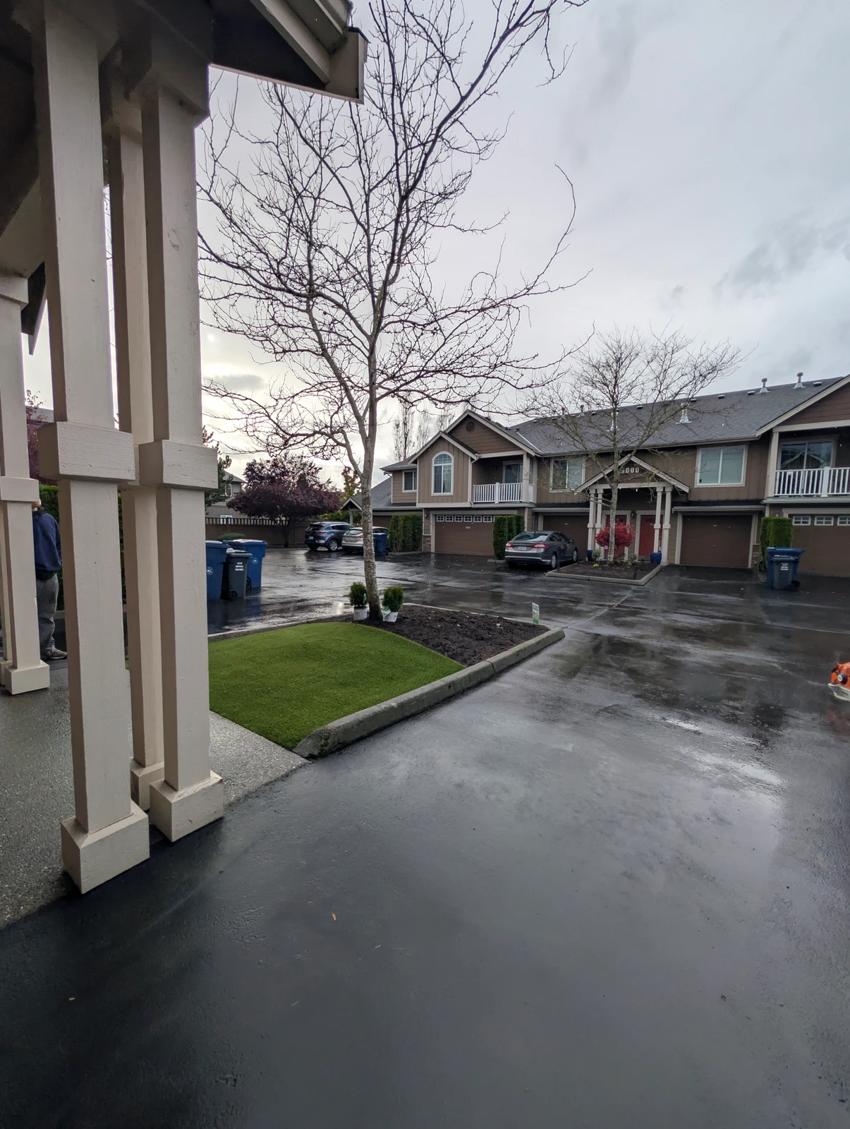 K9Grass Elite artificial pet turf patch installed in landscaped island, townhome complex, Marysville WA, rainy day